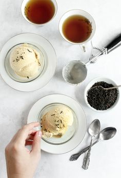 three plates with ice cream, tea and spoons next to each other on a table