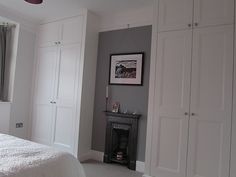 a white bed sitting in a bedroom next to a tall cabinet filled with drawers and a window