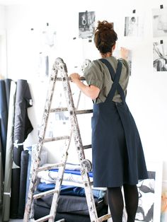 a woman is standing on a ladder and painting