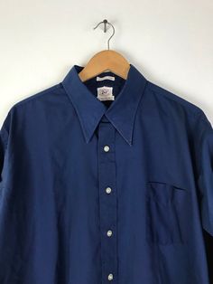 "-Description- >men's dark blue french cuff dress shirt >collared >button front >open pocket on the front >original print/stamp on bottom front of shirt >size XXL 17.5 >perfect for a formal event! >condition: ok condition - a good amount of wear on the collar - please see all photos before purchase >color(s): blue >fabric(s): 65 polyester / 35 cotton >brand: enro >care: machine wash -Measurements- >size: XXL 17.5 ✩ all measurements are taken with the item l Blue Shirt With Cuffed Sleeves And Spread Collar, Vintage Long Sleeve Business Shirt, Vintage Fitted Business Shirt, Classic Blue Shirt With Cuffed Sleeves, Vintage Blue Shirt For Work, Vintage Formal Collared Shirt, Vintage Collared Formal Shirt, Classic Blue Relaxed Fit Dress Shirt, Classic Blue Collared Dress Shirt