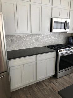 a kitchen with white cabinets and stainless steel appliances