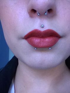 a woman with red lipstick and piercings on her nose