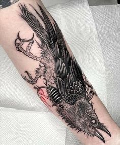 a black and grey bird tattoo on the arm