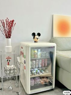 a mini fridge with mickey mouse magnets on the front and side doors, in a living room