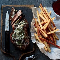 steak and french fries on a tray next to a cup of tea, knife and fork