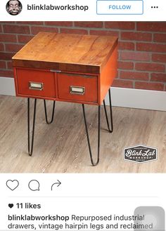 an orange side table with two drawers and hairpin legs in front of a brick wall