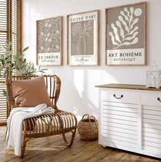 three framed art prints hang on the wall above a chair and sideboard in a white room