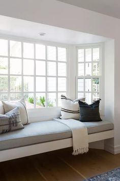 a white window seat with pillows on it