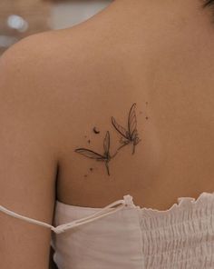 the back of a woman's shoulder with a small dragonfly tattoo on it