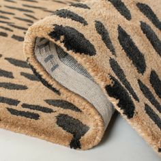 an animal print rug is laying on top of a white surface with a black and gray stripe