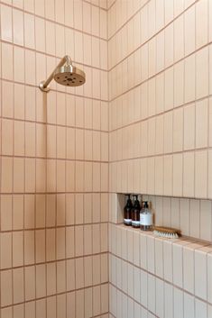 a bathroom with a shower head, soap and lotion bottles on the shelf next to it