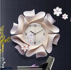 a wall clock with flowers on it in the middle of a room next to a chair