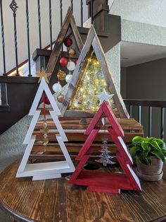 three wooden christmas trees sitting on top of a table next to a bannister