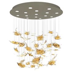 a chandelier that is hanging from the ceiling with gold leaves on it and white circles