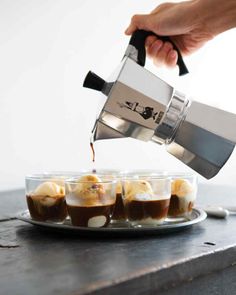 someone pouring coffee into small cups on a plate