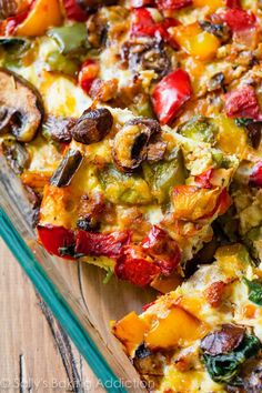 a casserole dish with vegetables and cheese on a wooden table, ready to be eaten