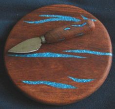 a knife is on top of a wooden board with blue glitters in the paint