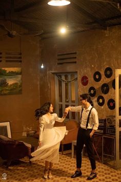 a man and woman dancing in a room with record records on the wall behind them