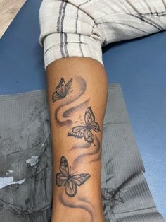 a person with a tattoo on their arm and butterfly tattoos on the leg, sitting on a bed