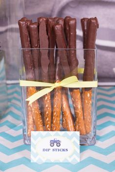 chocolate covered pretzels are in a clear container with a yellow ribbon around it