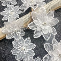 some white flowers are sitting on top of a roll of fabric next to an old book