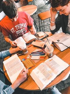 two young men sitting at a table with books and pencils in front of them