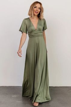 a woman in a green dress posing for the camera with her hands on her hips