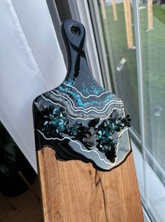 a black and blue cutting board sitting on top of a wooden stand next to a window