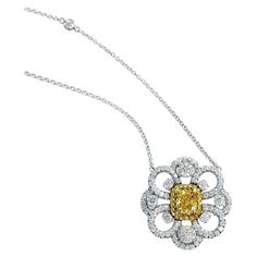 Introducing a captivating flower-inspired open-style design pendant necklace adorned with a center of 0.73-carat cushion-cut Fancy Vivid Yellow diamond, certified by GIA with an SI1 clarity rating. This remarkable centerpiece is encircled by a halo of 22 round brilliant yellow diamonds, accompanied by an additional 92 colorless diamonds boasting G color and VS-SI clarity, weighing 1.23 carats. The pendant gracefully suspends from a Diamond station necklace, reminiscent of the 'Diamond by the Yar Diamond By The Yard, Novel Collection, Yellow Diamonds, Diamond Supply, Colorless Diamond, Station Necklace, Rough Diamond, Diamond Pendant Necklace, Fancy Color Diamonds