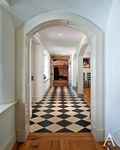 an arched hallway leading to a kitchen and dining room area with black and white checkered flooring