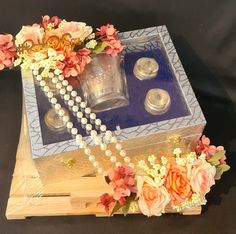 a wooden box with flowers and pearls on the lid, next to two silver cups