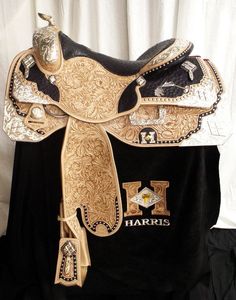 a black shirt with gold and white designs on the front has a cowgirl's name written on it