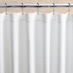 a white shower curtain hanging from a metal rod