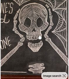 a chalk drawing of a skull and two crossed bones on a blackboard with the words halloween comes one above it