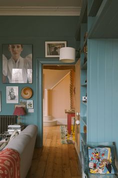 a living room with blue walls and pictures on the wall above the couch, along with bookshelves