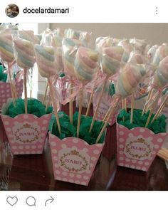 there are many candy lollipops in pink and green wrappers on the table