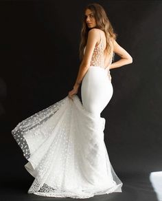 a beautiful woman in a white dress posing for the camera with her back to the camera