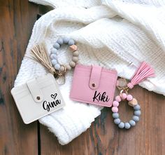 two pink and white purses sitting on top of a wooden floor next to a keychain