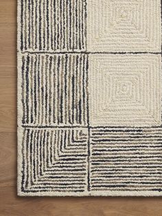 an area rug with squares and lines on top of wooden flooring, viewed from above