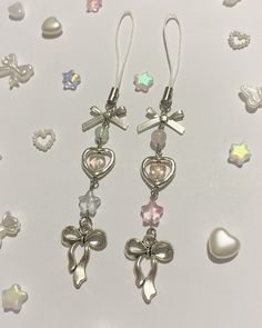 two pairs of earrings with bows, hearts and cross charms on white background surrounded by other jewelry items