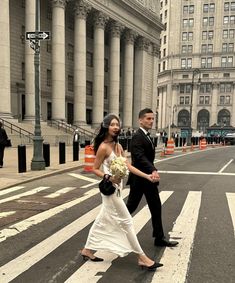 a bride and groom walking across the street