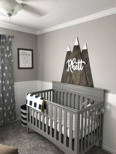 a baby's room with mountains on the wall and a crib in the corner