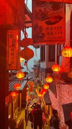 people walking down an alley with lanterns hanging from the ceiling