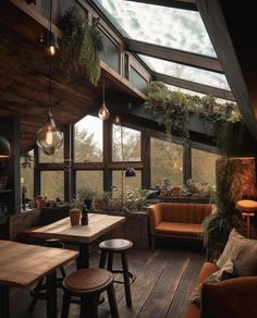 a room filled with lots of windows and furniture next to a wooden floor covered in plants