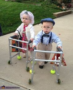 two small children are playing with their walkers on the sidewalk in front of some grass