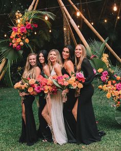 a group of women standing next to each other in front of an arch with flowers