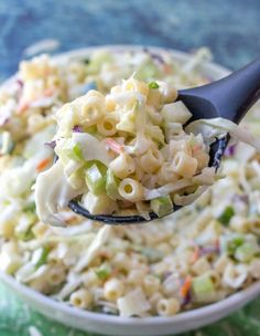 a spoon full of macaroni salad on top of a green cloth covered table