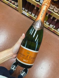 a person holding a bottle of wine in front of shelves with shoes on them and other bottles