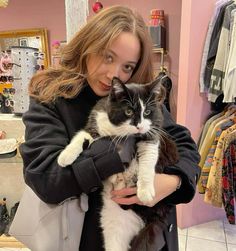 a woman holding a black and white cat in her arms