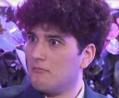 a close up of a person wearing a suit and tie with flowers in the background